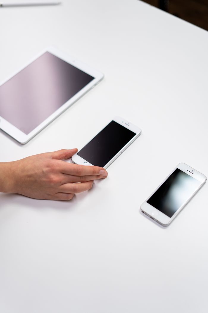 Vue de dessus d’un espace minimaliste avec une tablette et des smartphones posés sur une surface blanche.