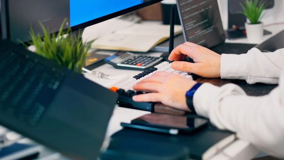A close-up of a modern workspace, featuring a laptop and smartphone in use.